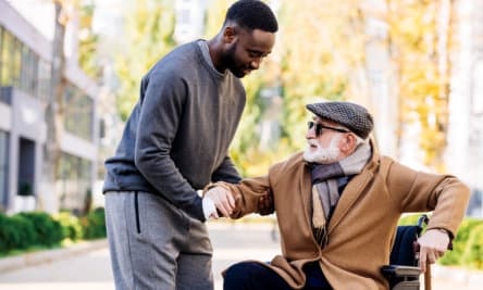 caregiver assisting senior man to stand