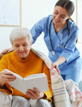 caregiver giving blanket to a senior woman