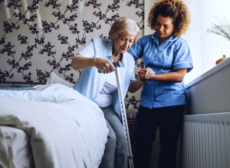 caregiver assisting senior woman to stand