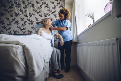 caregiver assisting senior woman making clothes