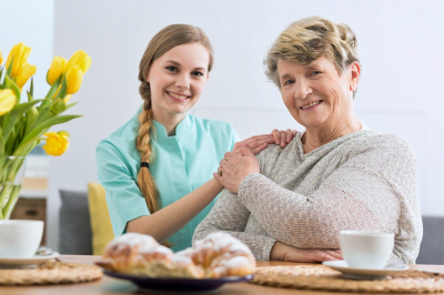 senior woman and caregiver smiling