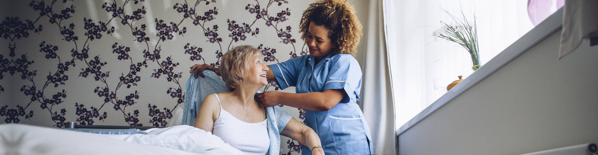 caregiver assisting senior woman making clothes